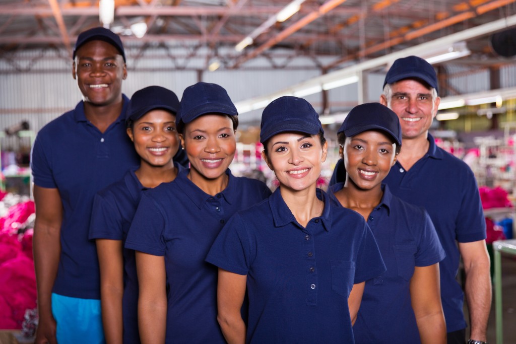 group of happy clothing factory workers inside production area