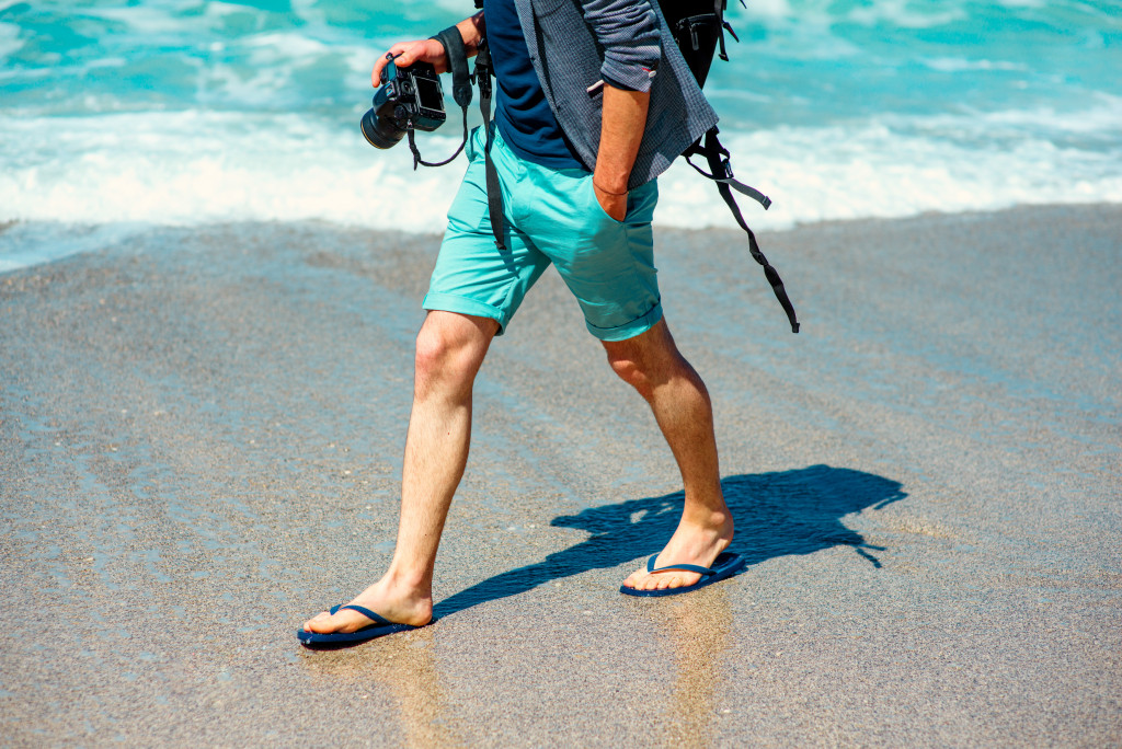 man wearing slippers walking at the beach