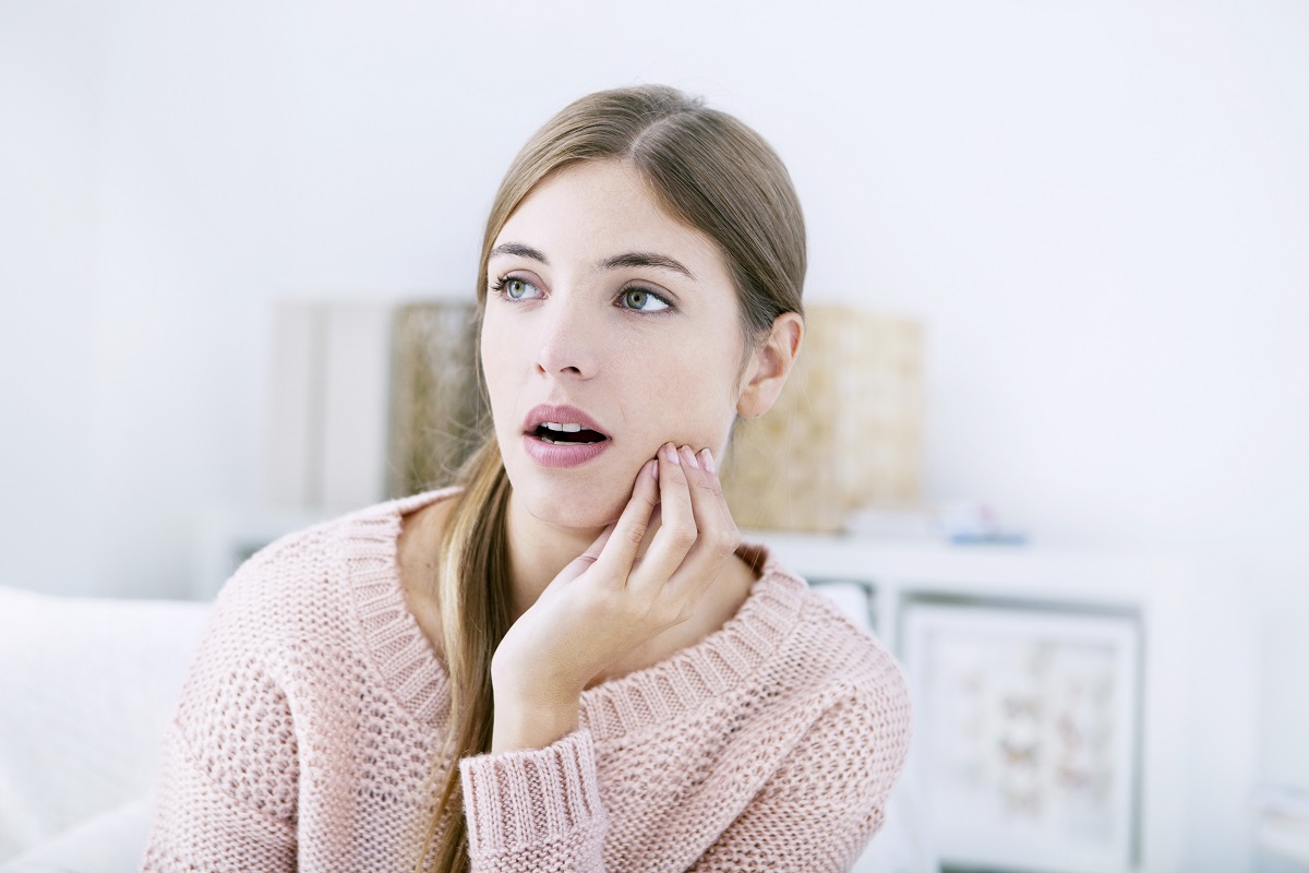 woman with her hand on her cheek in pain