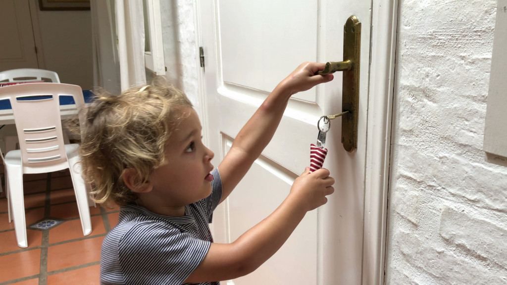 A young child trying to open a door with a key