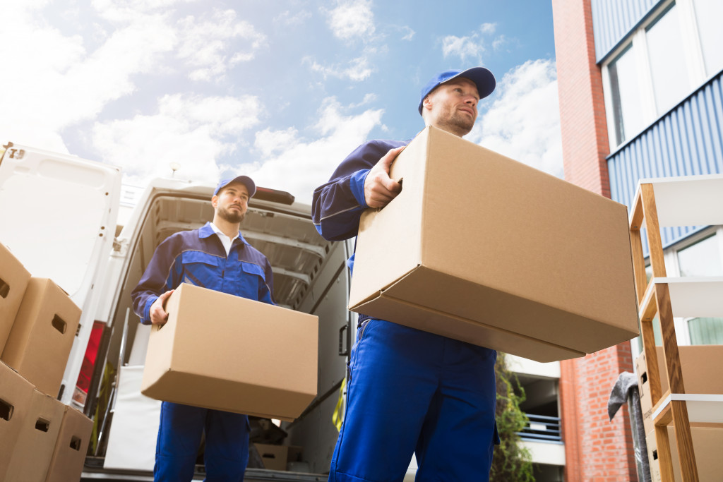 male movers in uniform carrying boxes