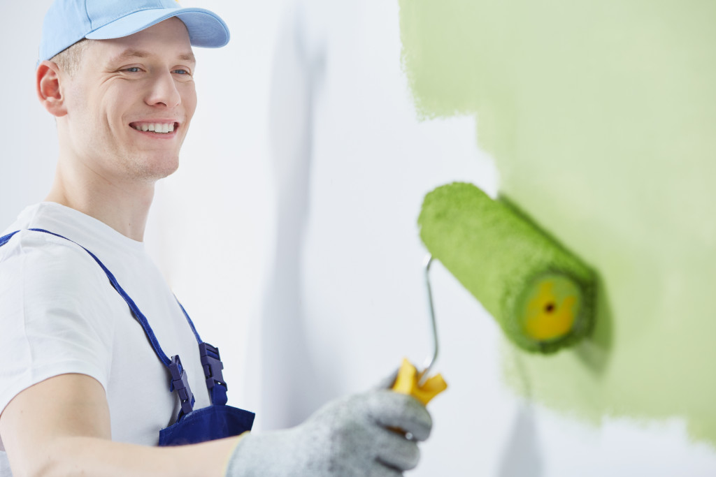 A professional painter painting a wall green