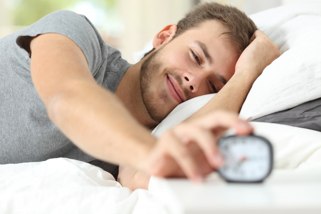 A man turns off his alarm as he wakes up from sleep