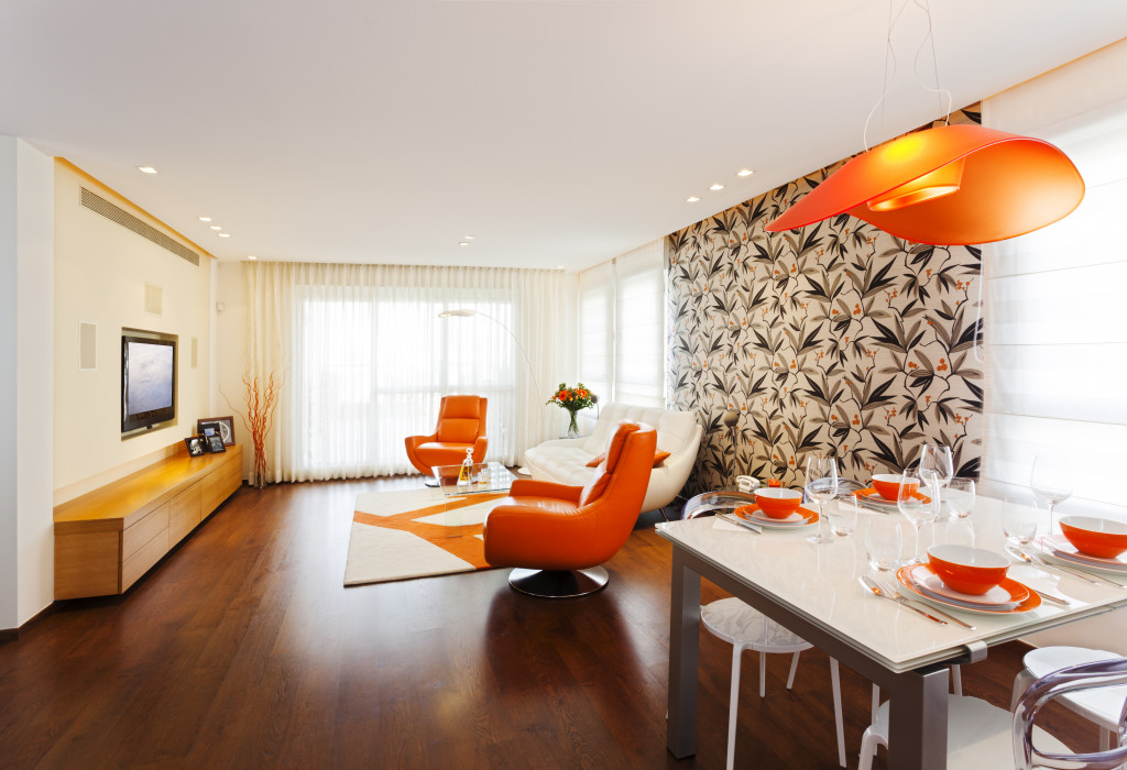 A modern living and dining room with orange and brown colors