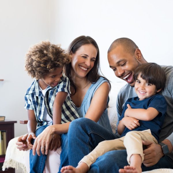 happy multiracial family sitting in sofa with two children