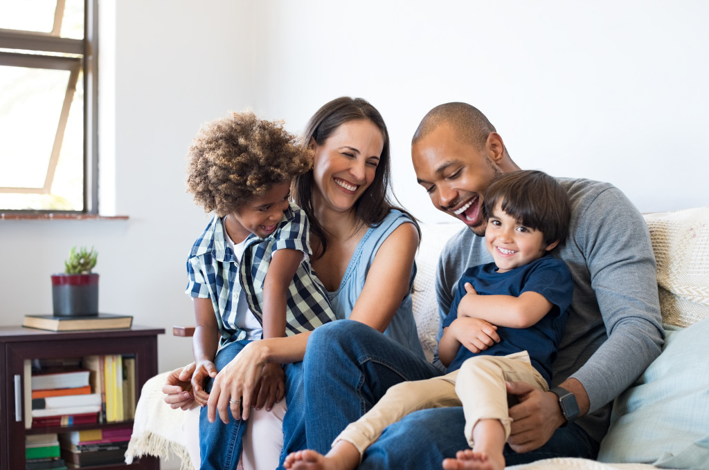 happy multiracial family sitting in sofa with two children