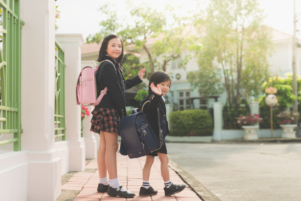 Young children in school uniform carrying backpacks on the way to school