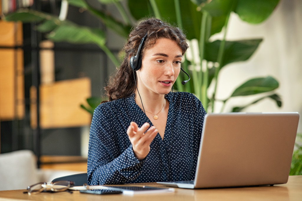 a young adult speaking in front of a laptop