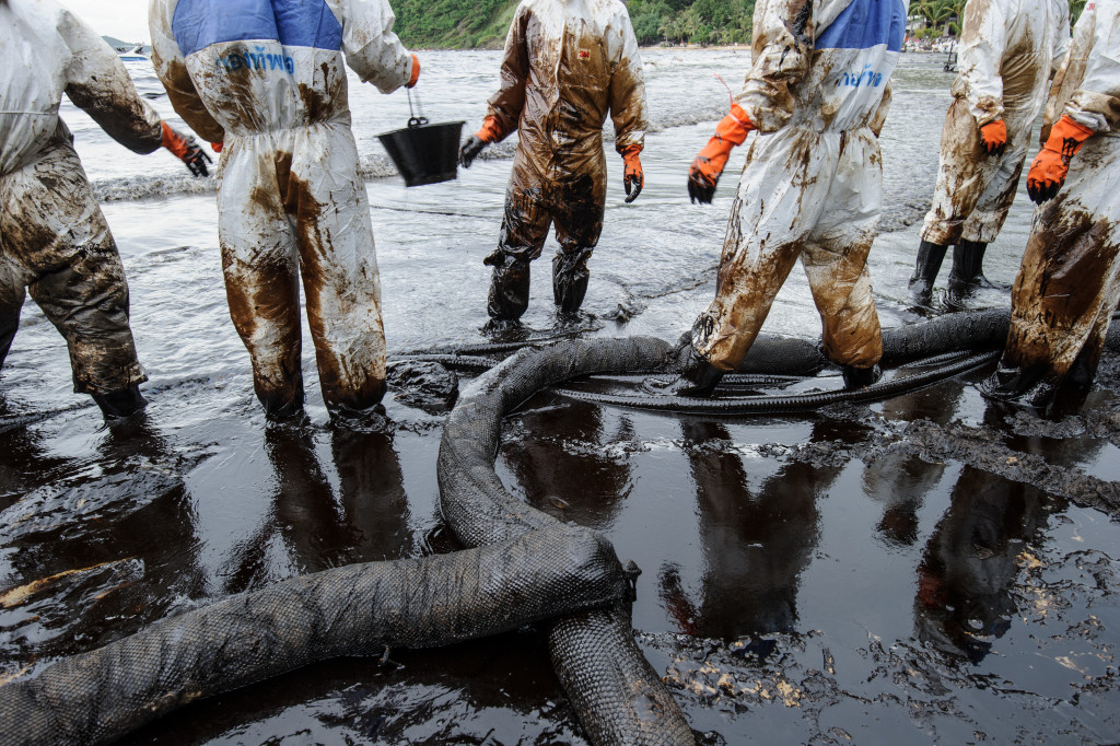 Workers cleaning up an oil spill at a beach.